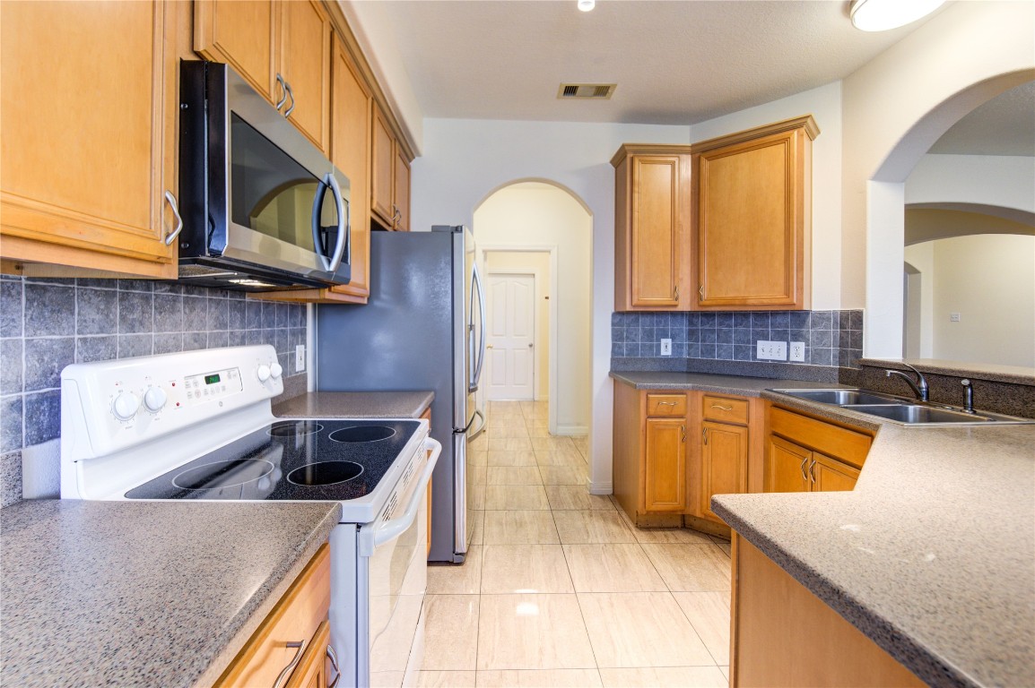 7611 South Linpar Court Houston, TX 77040 - Photo 16 of 49 a kitchen with stainless steel appliances granite countertop a stove a sink and a microwave