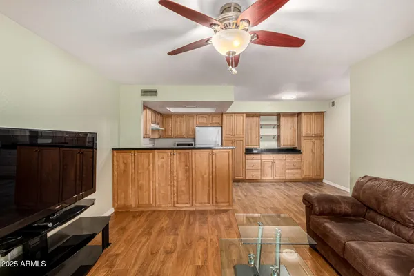 a living room with couches and kitchen view with wooden floor