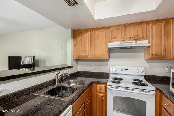a kitchen with granite countertop a sink a stove and cabinets