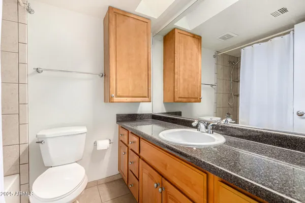 a bathroom with a granite countertop sink toilet and mirror