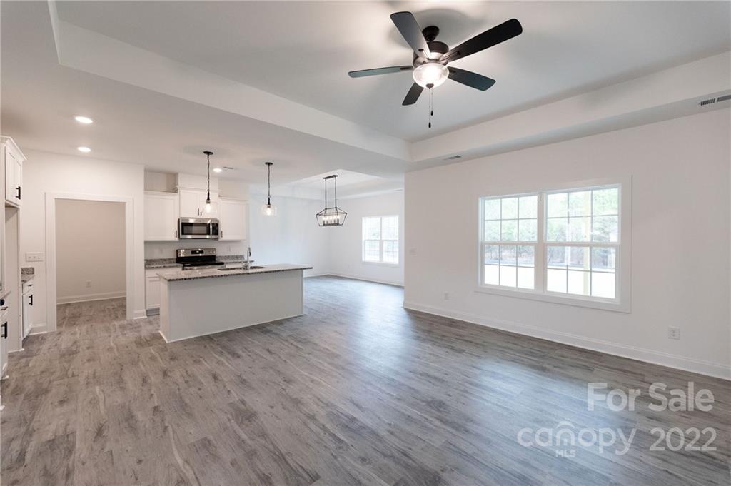 2231 State Rd S-46-1474, Unit 17 Clover, SC 29710 - Photo 3 of 20 a large kitchen with stainless steel appliances kitchen island a stove a refrigerator a sink a dining table and chairs with wooden floor