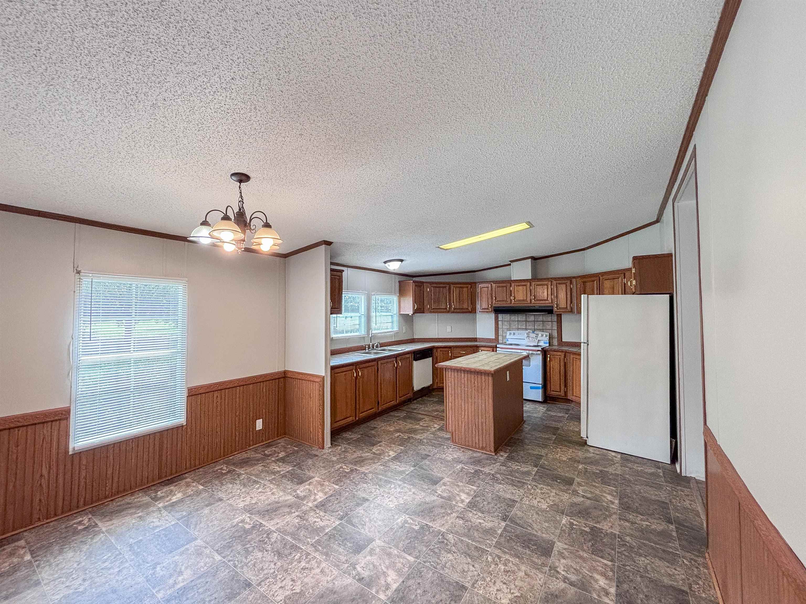 2847 Holly Grove Road Covington, TN 38019 - Photo 9 of 36 Open-concept kitchen and dining area featuring wood-finish cabinetry, a central kitchen island, an integrated kitchen appliance package, and durable tiled flooring