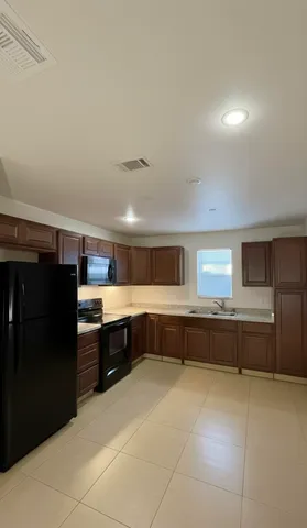 a large kitchen with stainless steel appliances a refrigerator and wooden cabinets