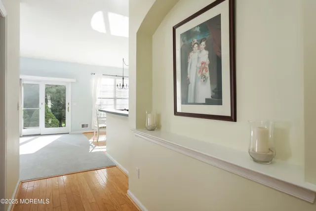 a view of a hallway with wooden floor and a large mirror