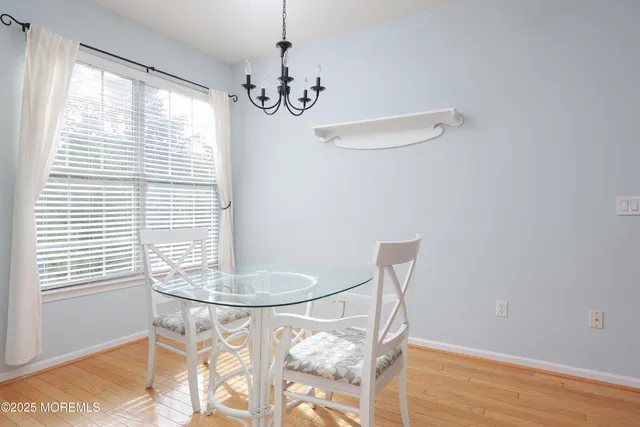 a dining room with chandelier and wooden floor