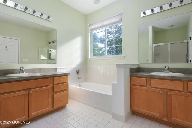 a bathroom with a granite countertop sink mirror bathtub and double
