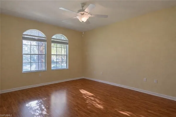 a view of empty room with wooden floor and fan