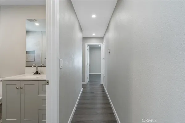 a view of a hallway with wooden floor and a bathroom