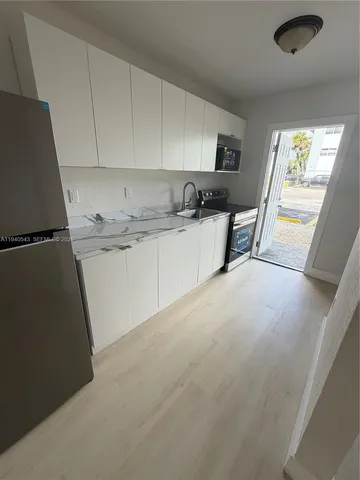 a large white kitchen with granite countertop a sink