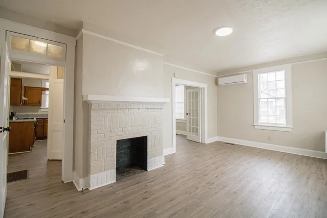 an empty room with wooden floor fireplace and windows