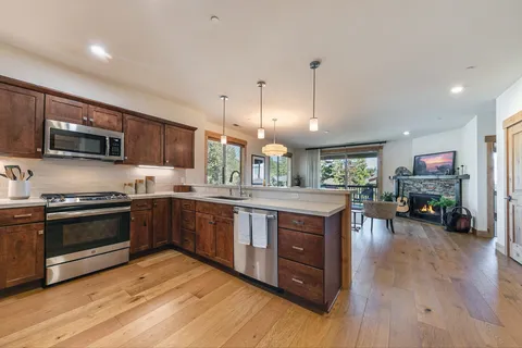 a kitchen with stainless steel appliances granite countertop wooden cabinets a sink a stove a dining table and chairs