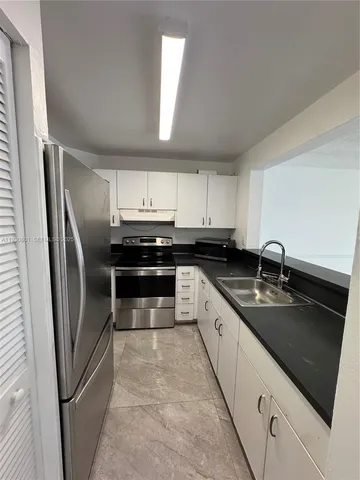 a kitchen with stainless steel appliances granite countertop a refrigerator a sink a stove a microwave and cabinets