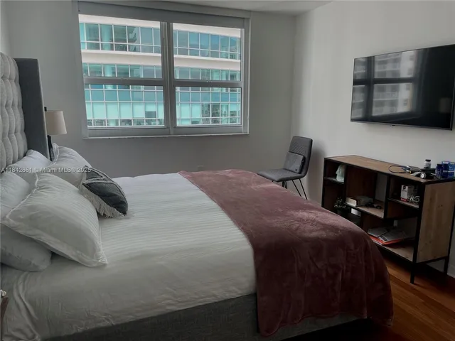 a bedroom with a bed a television and a window