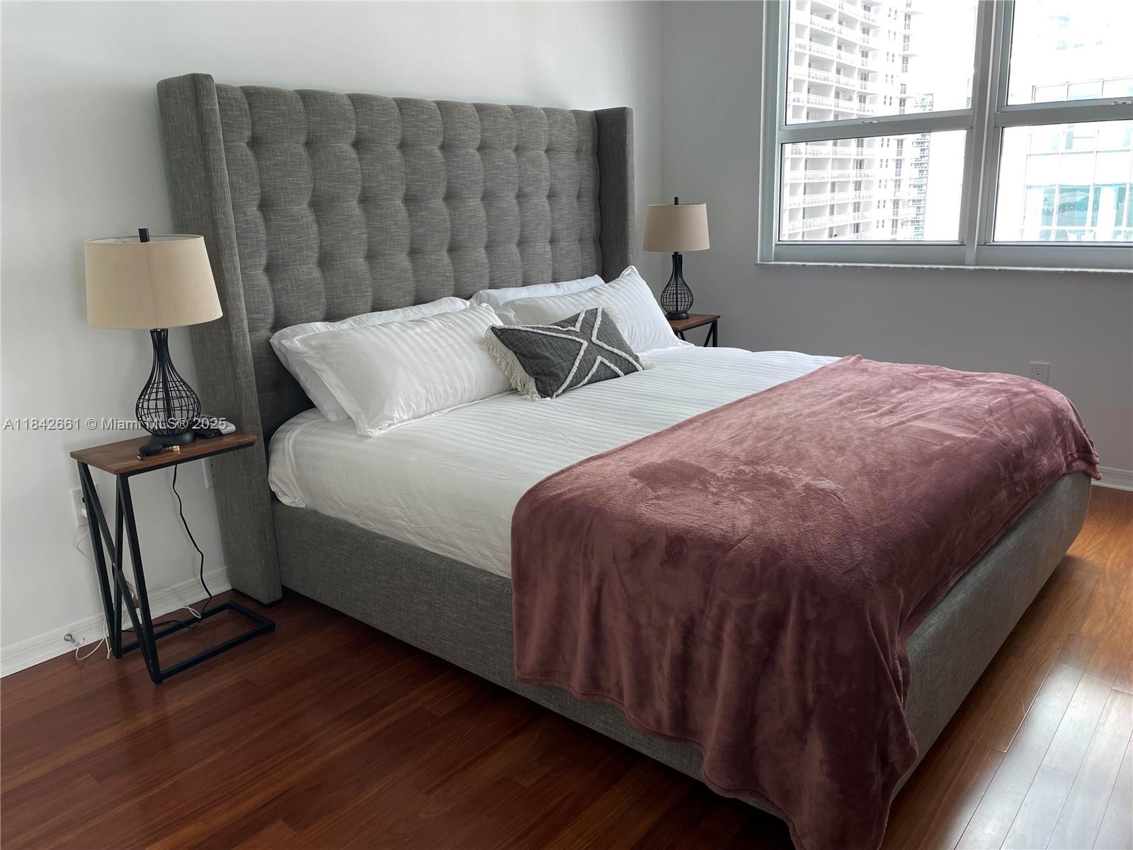 1155 Brickell Bay Drive, Unit 2802 Miami, FL 33131 - Photo 15 of 43 a bedroom with a bed a mirror and a window