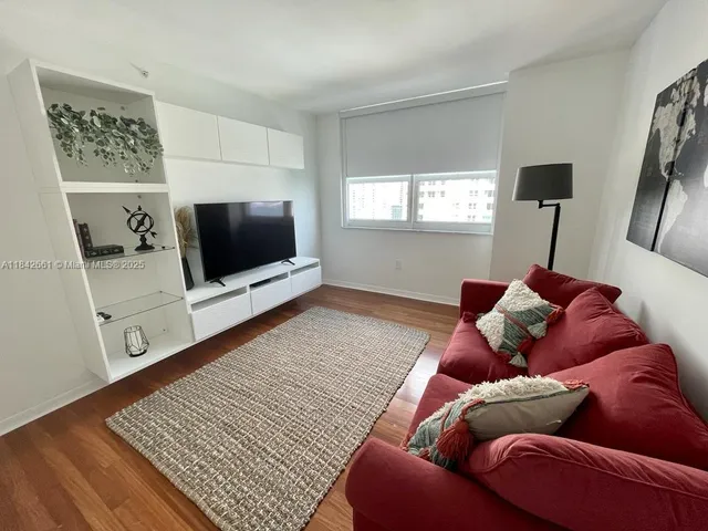 a living room with a bed and a flat screen tv