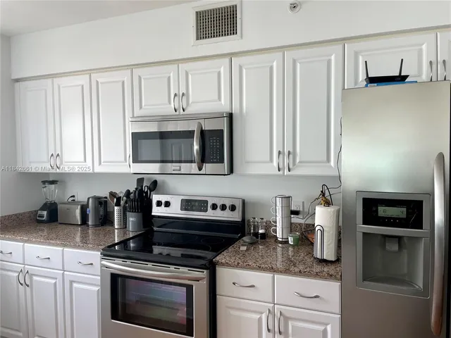 a kitchen with granite countertop white cabinets and stainless steel appliances