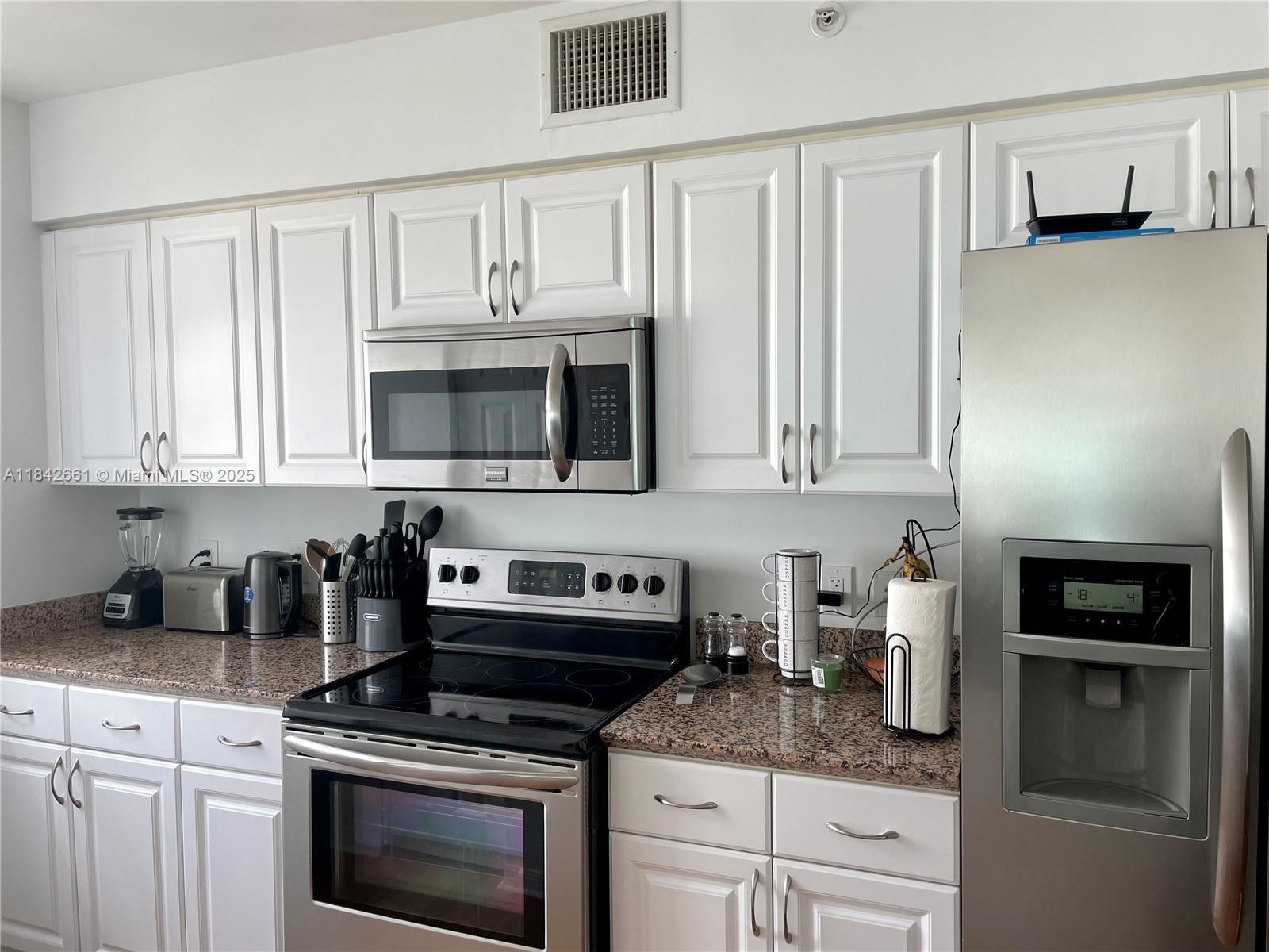 1155 Brickell Bay Drive, Unit 2802 Miami, FL 33131 - Photo 9 of 43 a kitchen with granite countertop white cabinets and stainless steel appliances