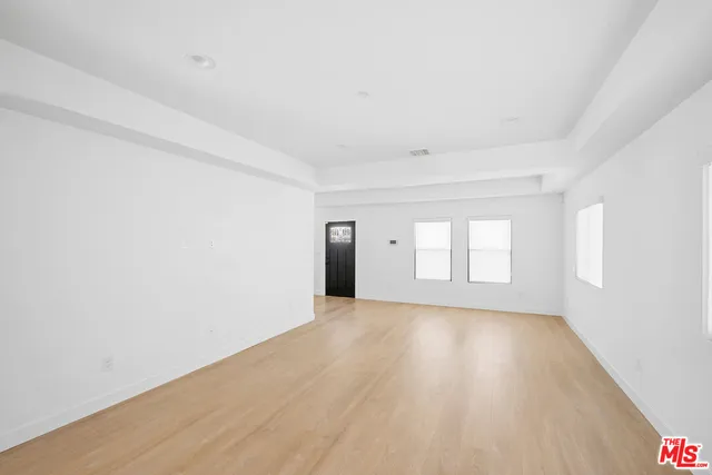 a view of an empty room with wooden floor and window