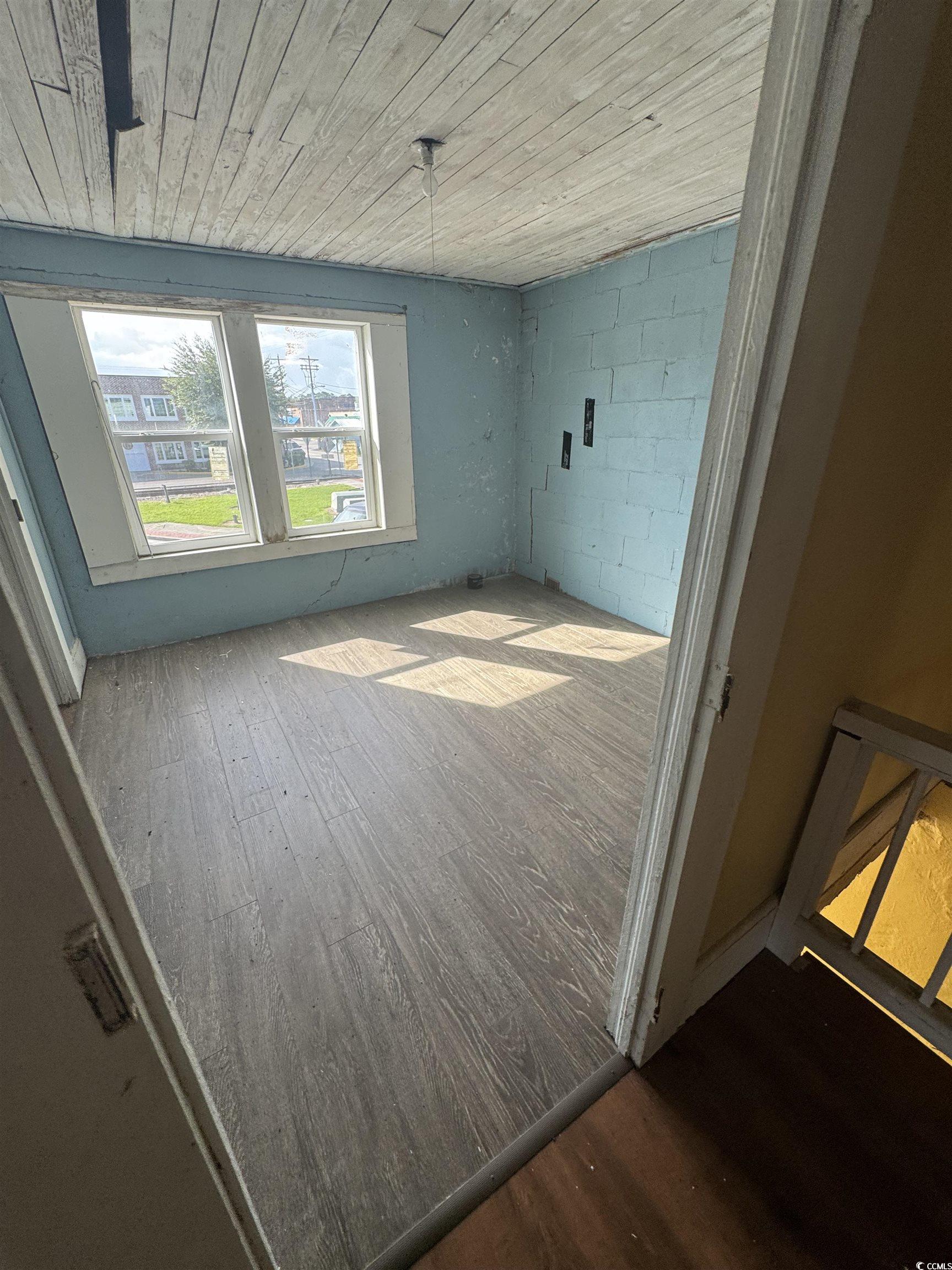 4211 Meeting Street Loris, SC 29569 - Photo 17 of 22 Unfurnished living room with dark wood-style flooring, concrete block wall, and wood ceiling
