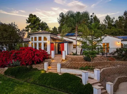 a front view of a house with a garden and trees