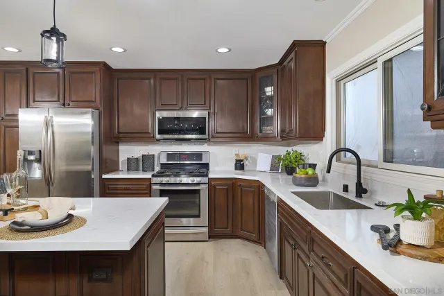 a kitchen with stainless steel appliances granite countertop a sink a stove top oven a refrigerator and a center island