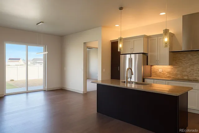 a kitchen with kitchen island a refrigerator and a sink
