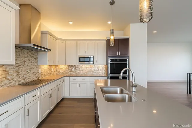 a large kitchen with granite countertop a sink and dishwasher a stove top oven with wooden floor