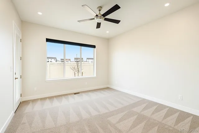 a view of empty room with window and ceiling fan