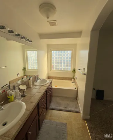 a bathroom with a tub double sink window and mirror