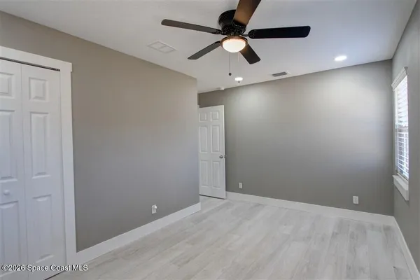 an empty room with ceiling fan and window