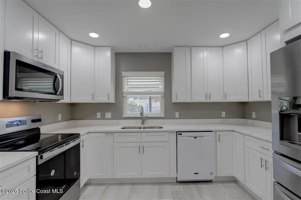 a kitchen with white cabinets stainless steel appliances and sink