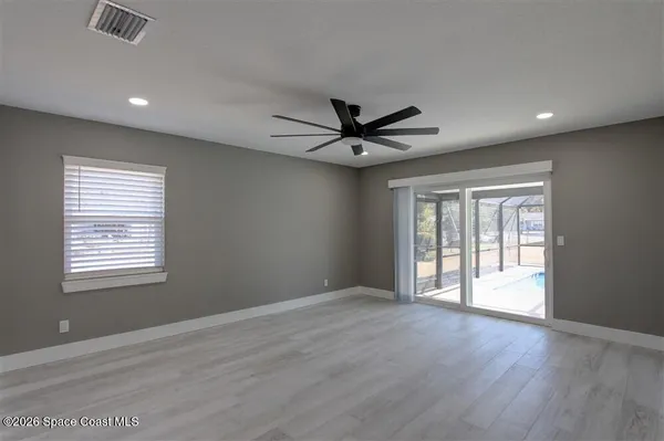 a view of an empty room with a window and wooden floor