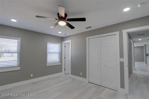 a view of an empty room with window and chandelier fan