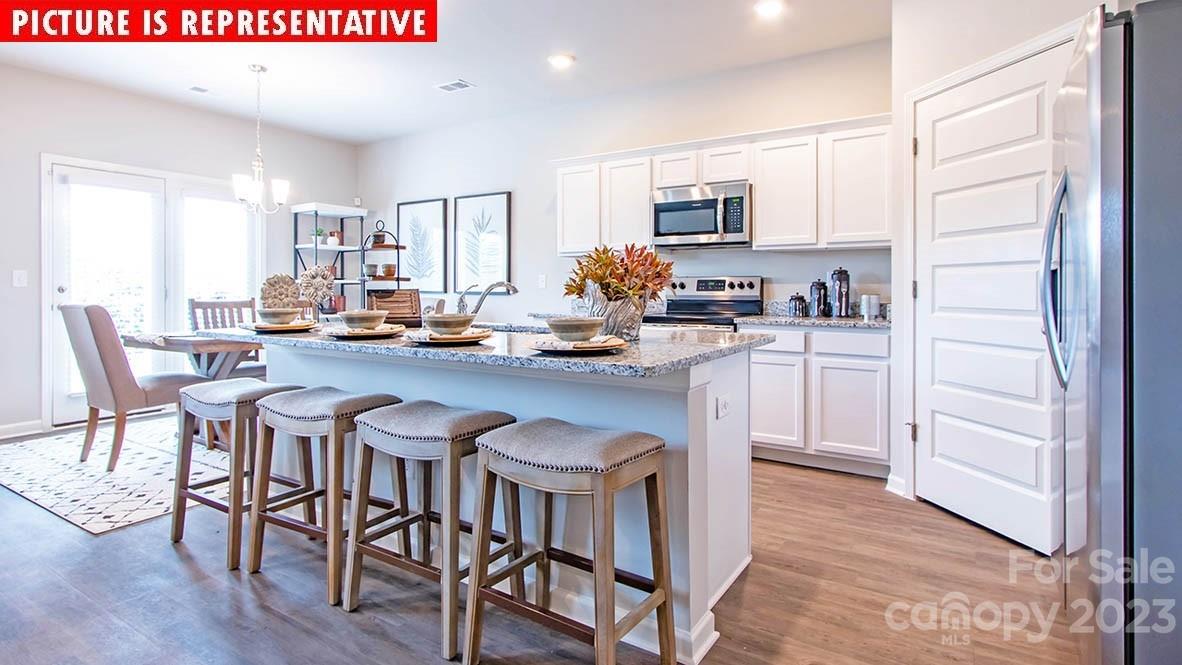 2147 Vanderlyn Street Monroe, NC 28112 - Photo 7 of 22 a kitchen with stainless steel appliances granite countertop a table chairs sink refrigerator and cabinets