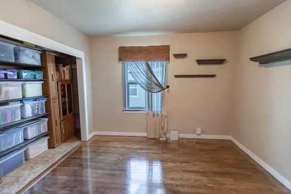 a view of empty room with wooden floor and book shelf