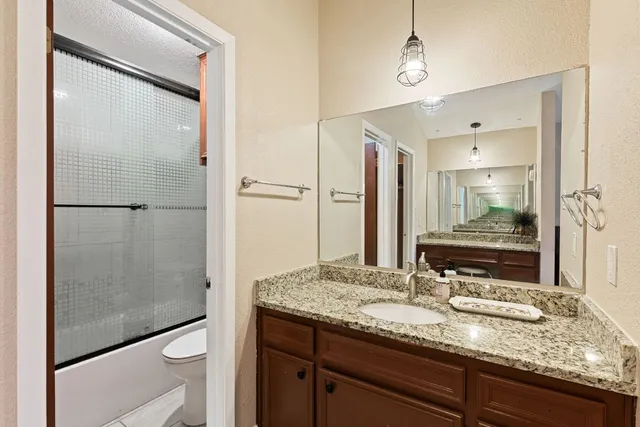a bathroom with a granite countertop sink toilet and shower