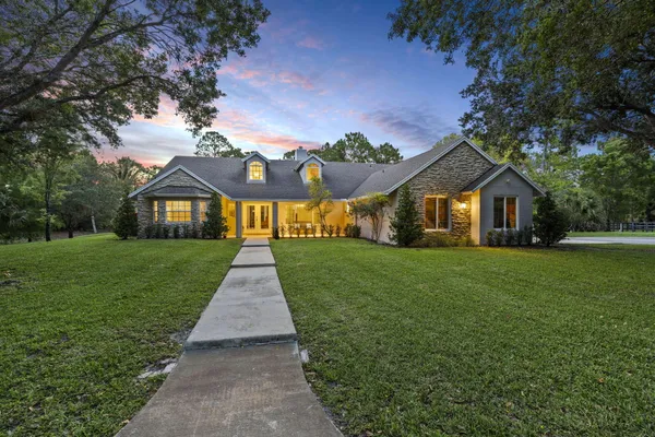 a front view of a house with a yard and garden
