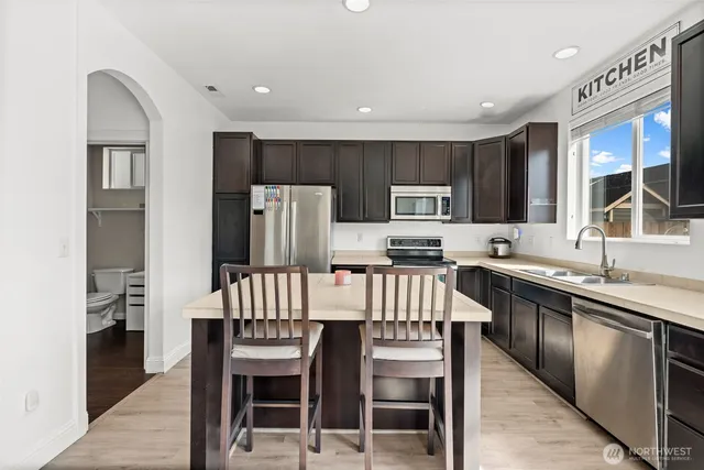 a kitchen with a refrigerator a stove a sink and chairs