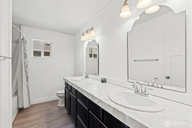 a living room with stainless steel appliances white cabinets and wooden floor