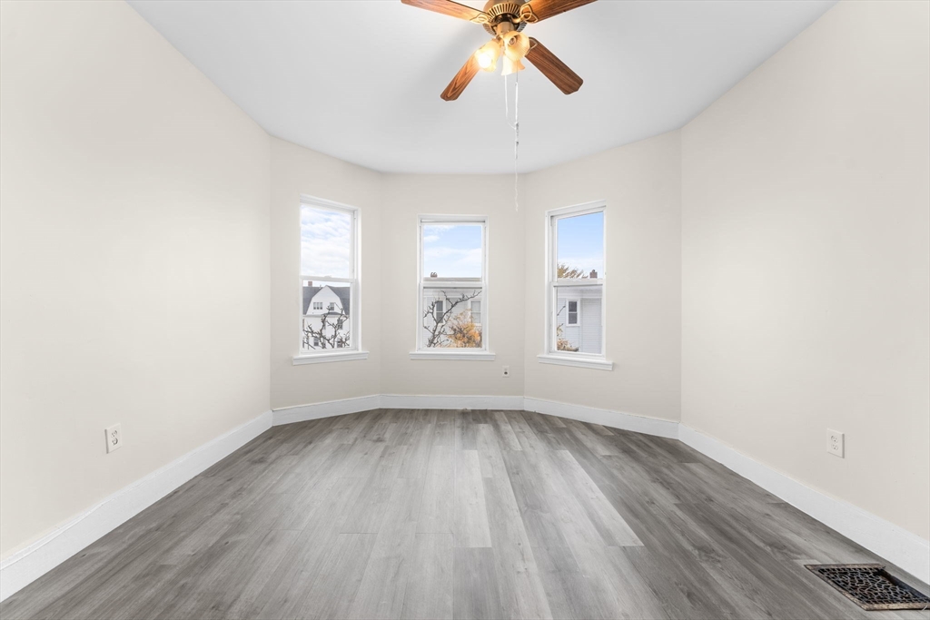 239 Bowdoin Street, Unit 3 Boston, MA 02122 - Photo 5 of 20 an empty room with wooden floor chandelier fan and windows