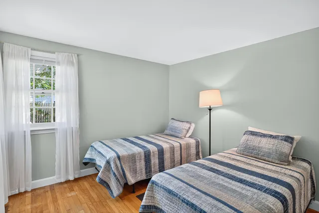 a bedroom with two beds lamp and a window