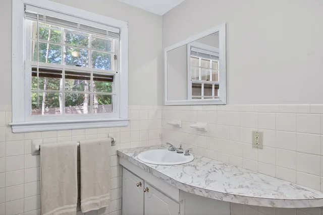 a bathroom with a granite countertop sink and a window