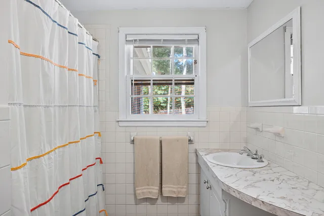 a bathroom with a granite countertop sink and a window