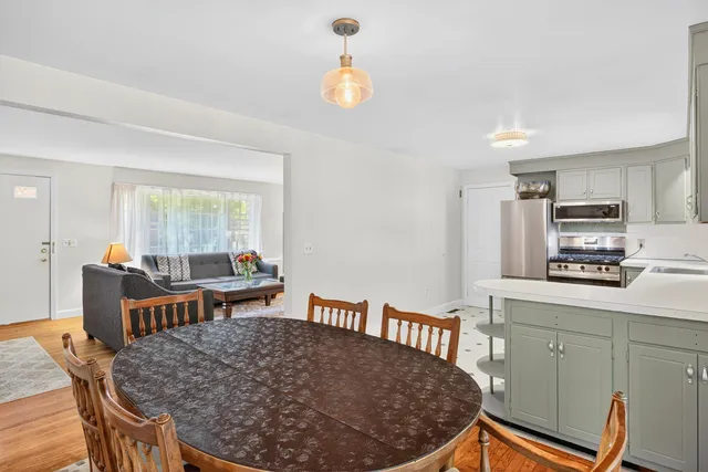 a kitchen with stainless steel appliances granite countertop a stove top oven a sink a dining table and chairs with wooden floor