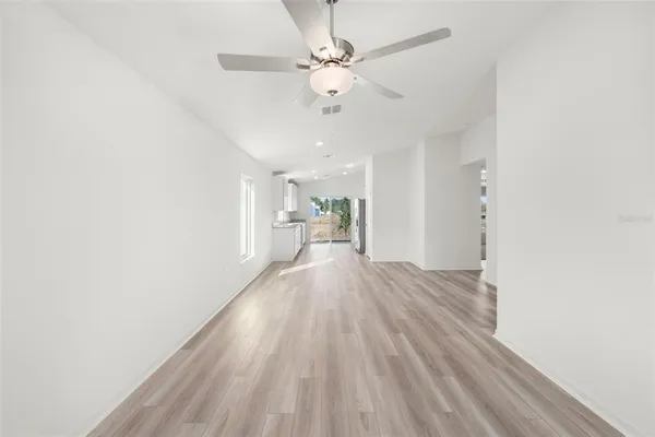 a view of a room with wooden floor and a ceiling fan