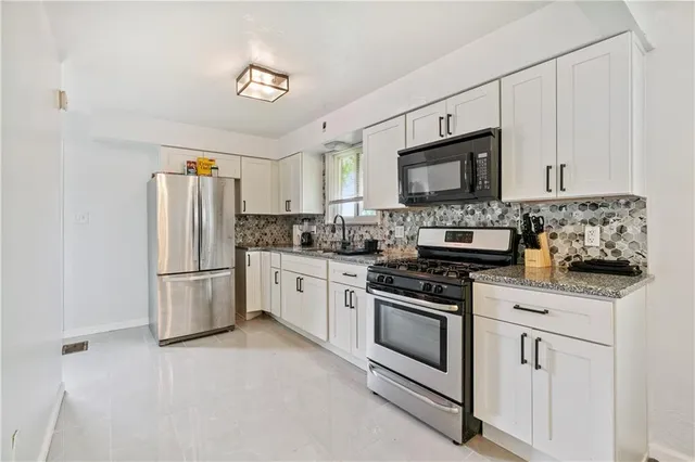 a kitchen with stainless steel appliances granite countertop a refrigerator stove a sink and a microwave