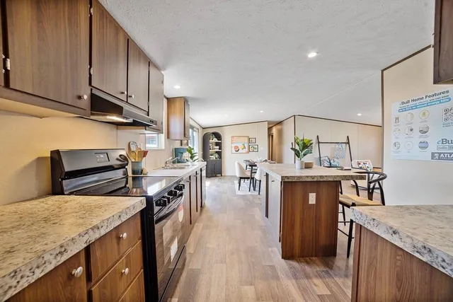 a kitchen with stainless steel appliances granite countertop a stove a sink dishwasher and cabinets with wooden floor
