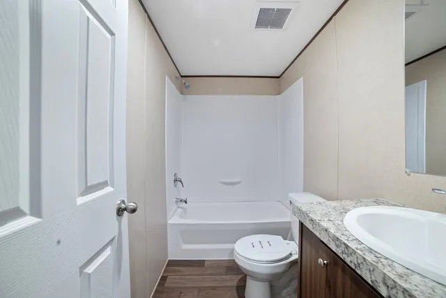 a bathroom with a granite countertop toilet sink and mirror