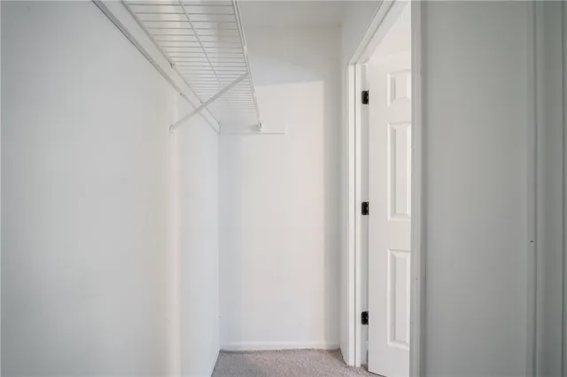 an empty room with a chandelier fan and windows