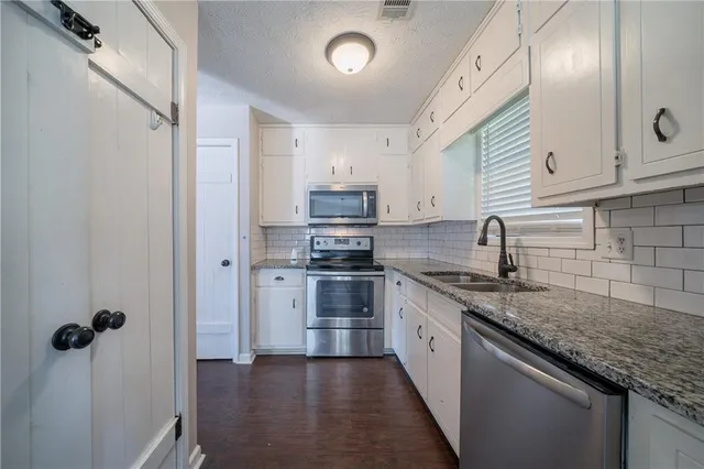 a kitchen with granite countertop stainless steel appliances a sink stove and refrigerator